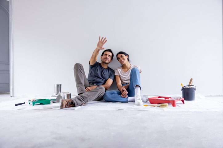 Couple taking a break from painting their house and sitting on the floor sharing ideas and day dreaming